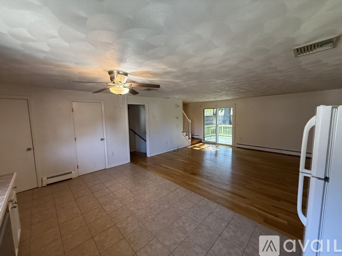 A spacious room with a ceiling fan and wooden flooring.