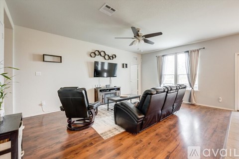 A living room with a row of black leather chairs facing a television.
