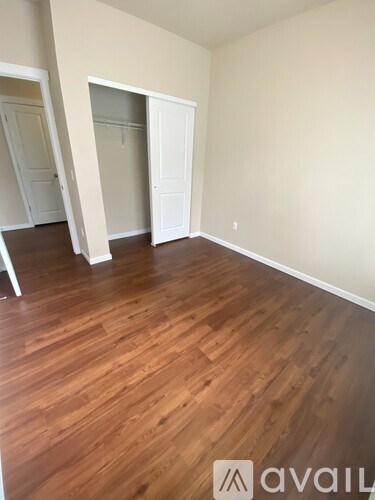 A room with wooden flooring and two open doors.