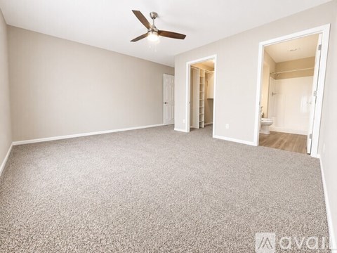 A room with a carpeted floor and a ceiling fan.