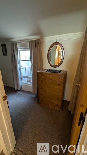 A bedroom with a dresser and a round mirror.