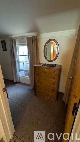 A bedroom with a dresser and a round mirror.