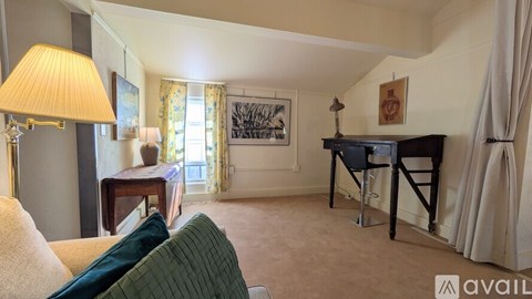 A living room with a couch, a lamp, a piano, and a painting on the wall.