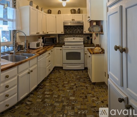 A kitchen with white cabinets and a tiled floor.