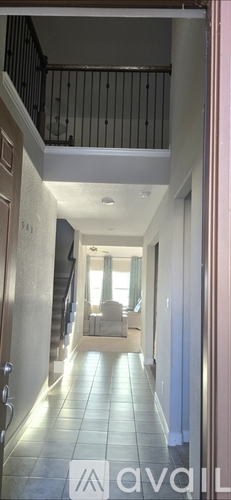 A hallway with a staircase and a chair.