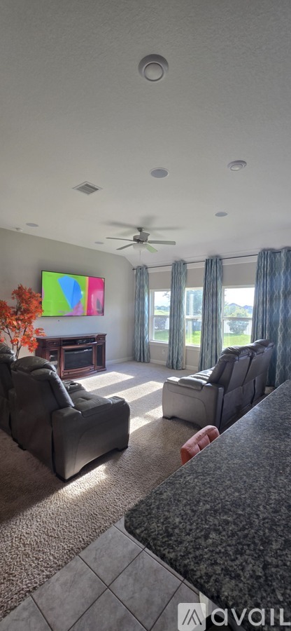 A living room with a grey couch and a television on the wall.