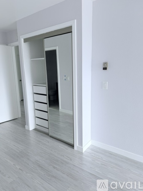 A white interior with a large mirrored wardrobe and drawers.