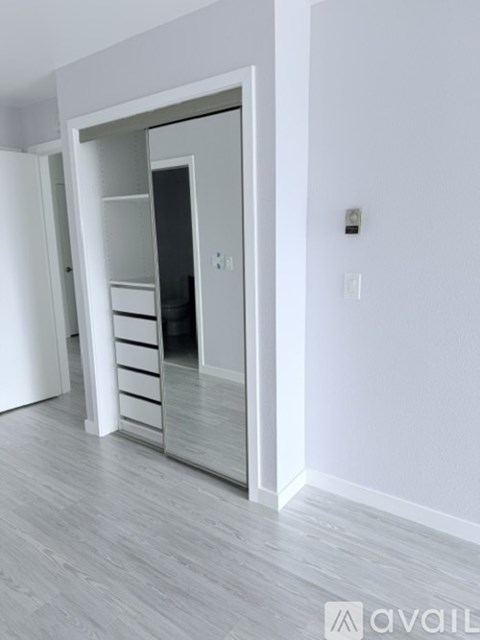 A white interior with a large mirrored wardrobe and drawers.