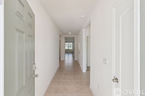 A long hallway with white walls and a tiled floor.