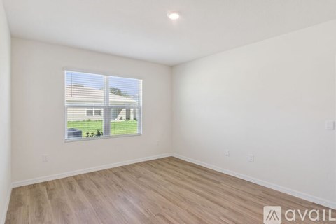 A room with a window showing a view of a house and trees.