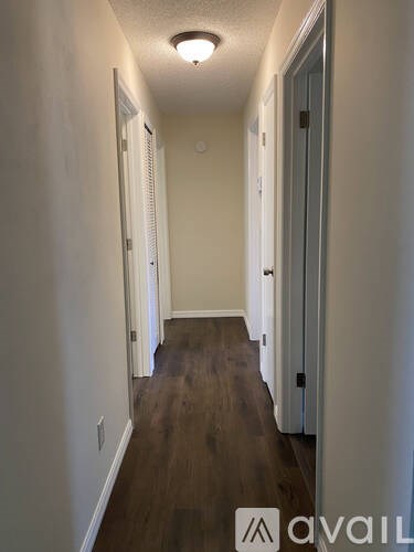 A hallway with wood floors and white walls.