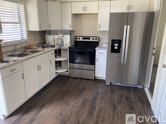 A kitchen with white cabinets and a stainless steel refrigerator.