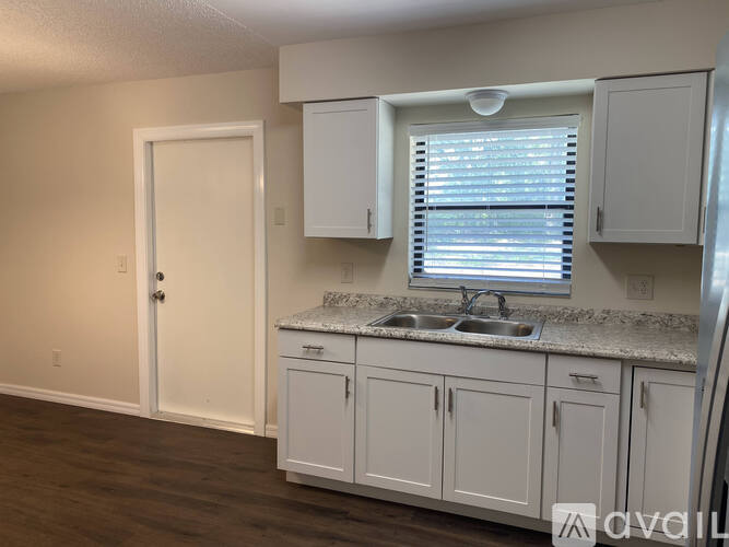 A kitchen with white cabinets and a granite countertop.