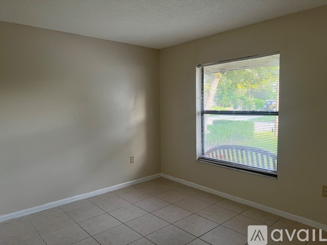 A room with a window showing a view of a lawn and trees outside.
