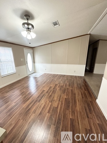 A room with wooden flooring and a window.