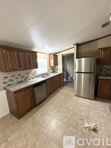 A kitchen with wooden cabinets and a stainless steel refrigerator.