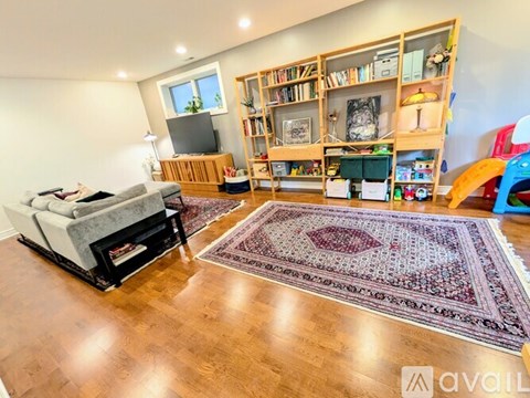 A living room with a grey sofa, a wooden bookshelf, and a rug on the floor.