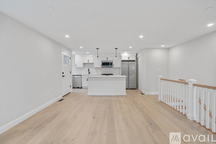 A spacious kitchen with white cabinets and a wooden floor.