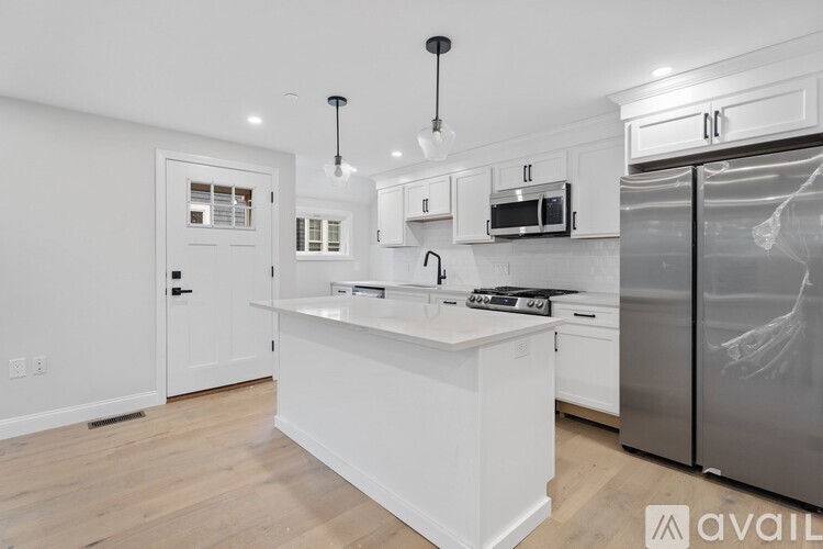A modern kitchen with white cabinets and stainless steel appliances.