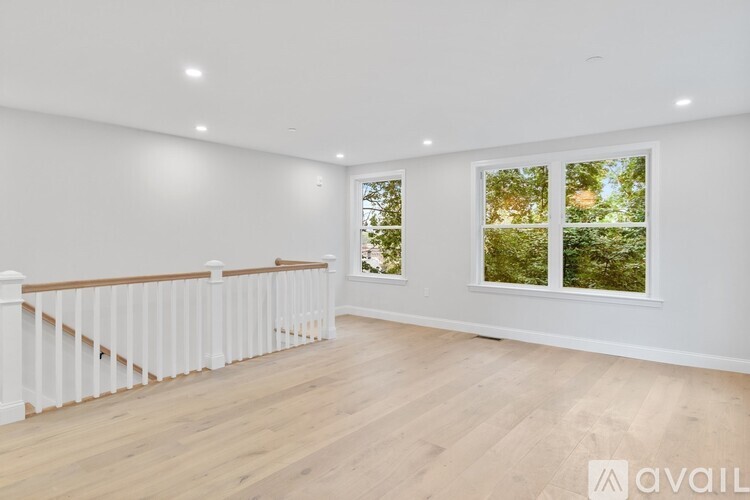 A spacious room with wooden floors and a white railing.