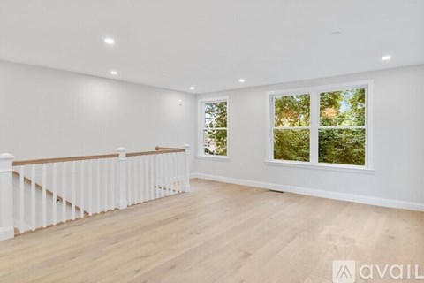 A spacious room with wooden floors and a white railing.