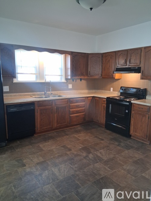 A kitchen with wooden cabinets and black appliances.