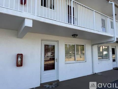 A white building with a balcony and a red fire extinguisher on the wall.