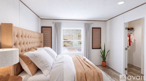 A bedroom with a large bed and a window with curtains.
