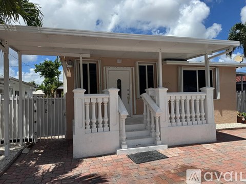 A white house with a porch and a gate.