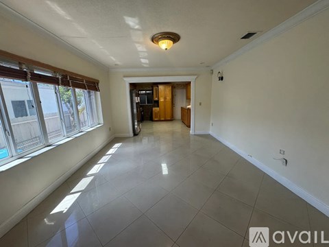 A spacious room with a tiled floor and a large window on the left side.