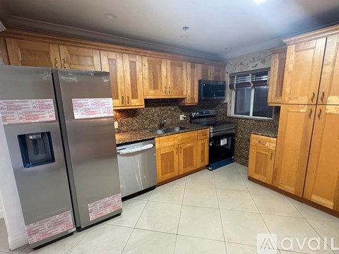 A kitchen with wooden cabinets and a stainless steel refrigerator.