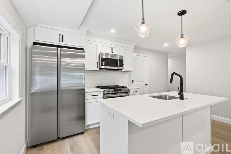 A modern kitchen with a white countertop and stainless steel appliances.