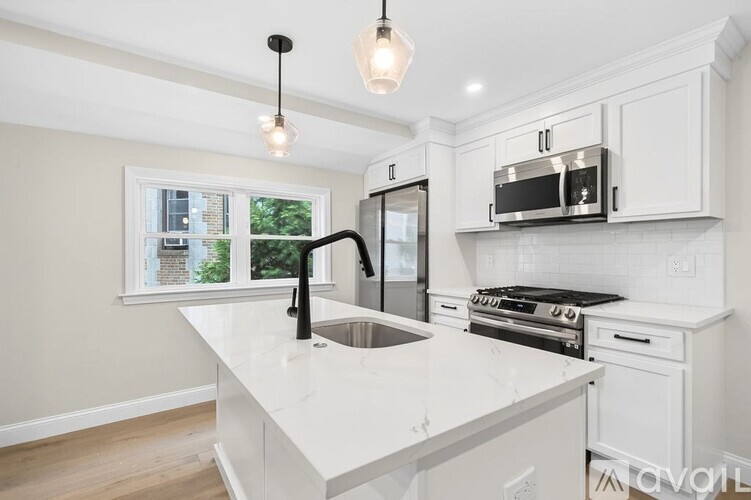 A kitchen with white cabinets and a black faucet.