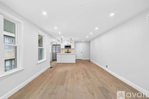 A spacious room with wooden flooring and white walls.