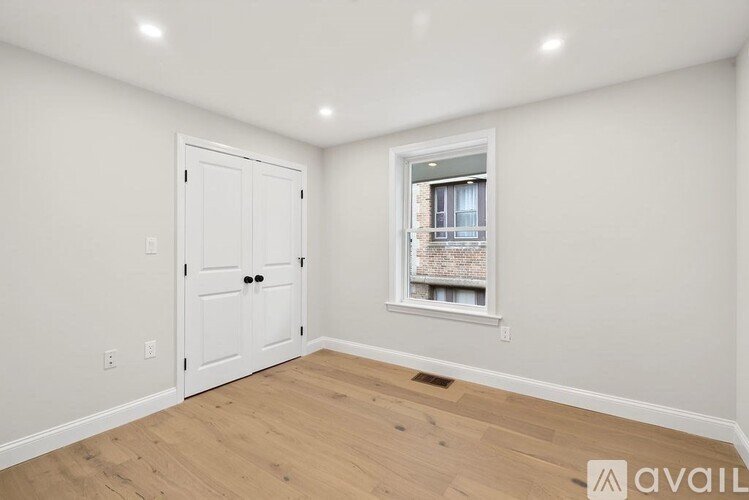 A room with a white door and a window with a view of a building outside.