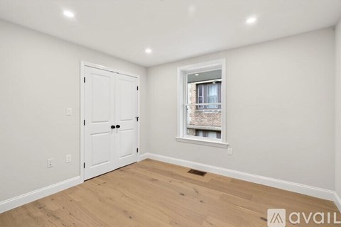 A room with a white door and a window with a view of a building outside.
