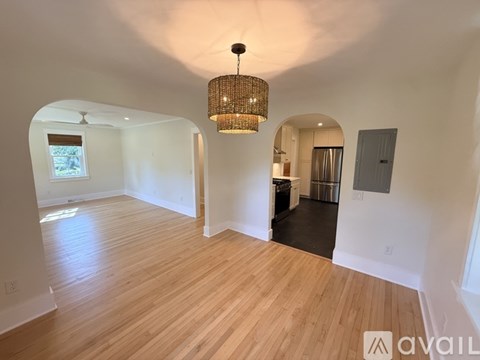 A large open room with wooden floors and a chandelier hanging from the ceiling.