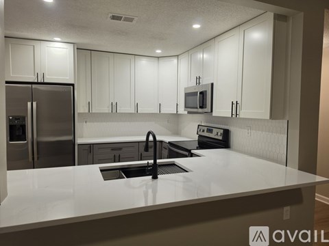 A modern kitchen with white cabinets and a stainless steel refrigerator.