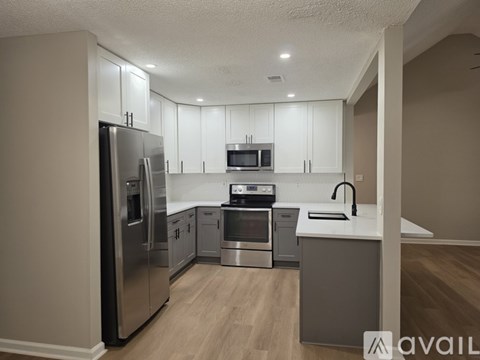 A kitchen with a refrigerator, microwave, oven, and sink.