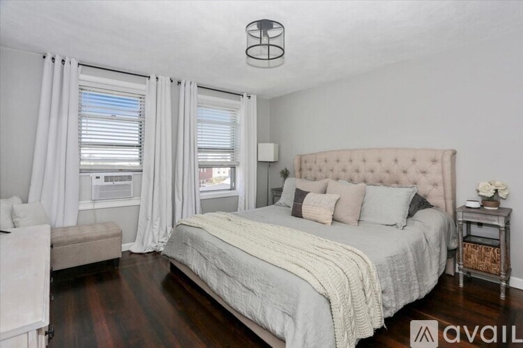 A bedroom with a large bed and a window with curtains.