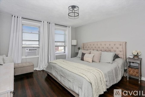 A bedroom with a large bed and a window with curtains.