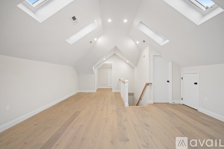 A spacious room with wooden floors and white walls, currently under renovation.