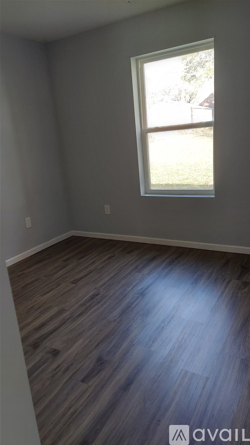 A room with a window and wooden flooring.
