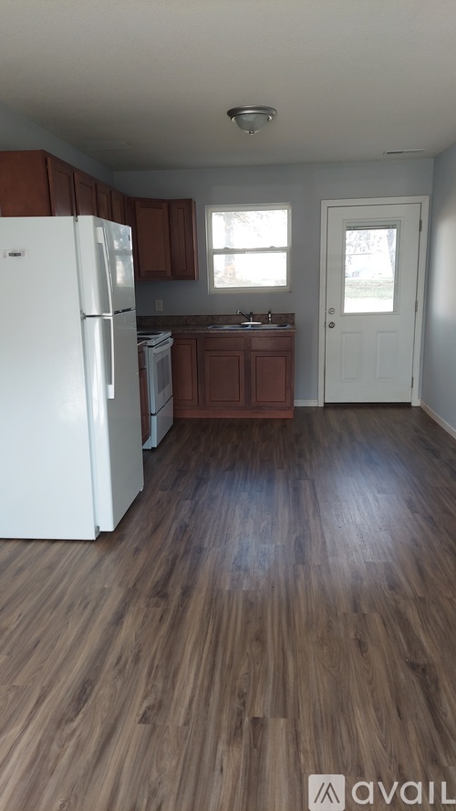A kitchen with a white fridge and wooden floors.