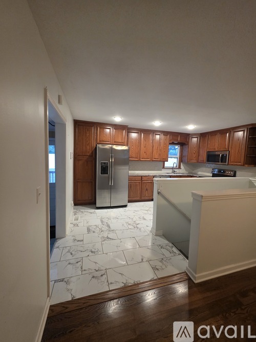 A kitchen with wooden cabinets and a marble floor.