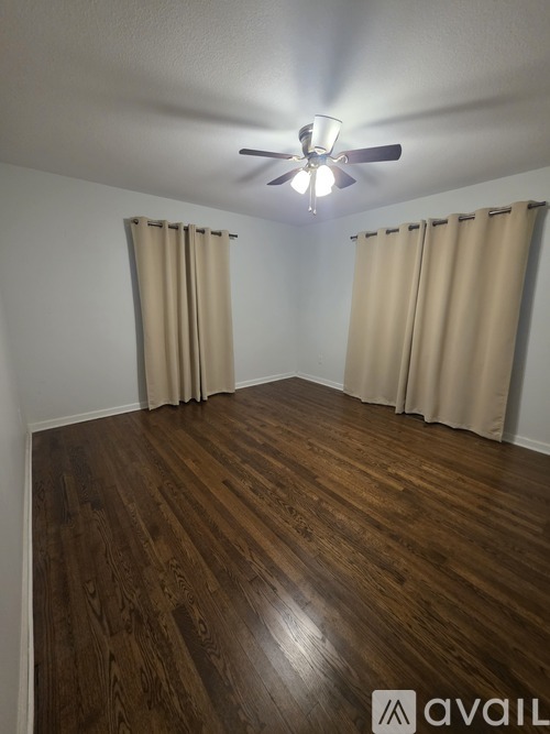 A room with wooden flooring and a ceiling fan.