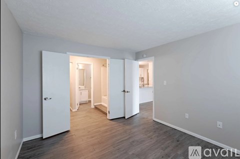 A room with white walls and wooden flooring, with a doorway leading to another room.