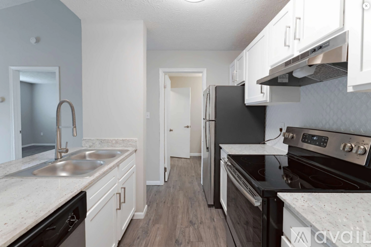 A kitchen with a black refrigerator and stove top oven.