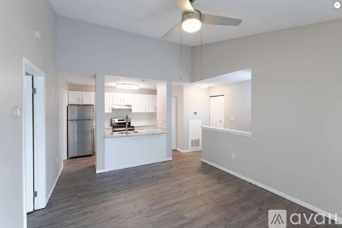 A spacious, empty room with a kitchen in the background.
