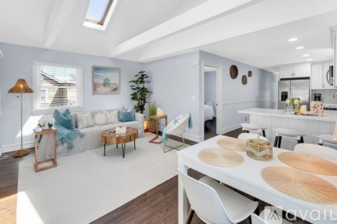 A well-lit, spacious kitchen and living room with a dining table and chairs.